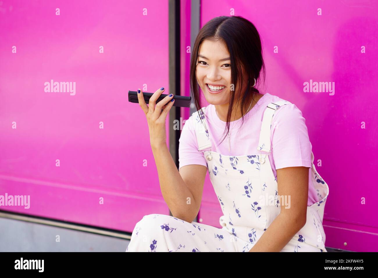 Cheerful Asian young woman using recording a voice note in her smartphone. Stock Photo