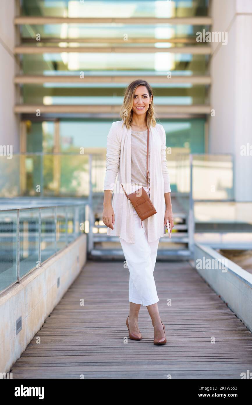 Stylish woman on footbridge outside modern building Stock Photo