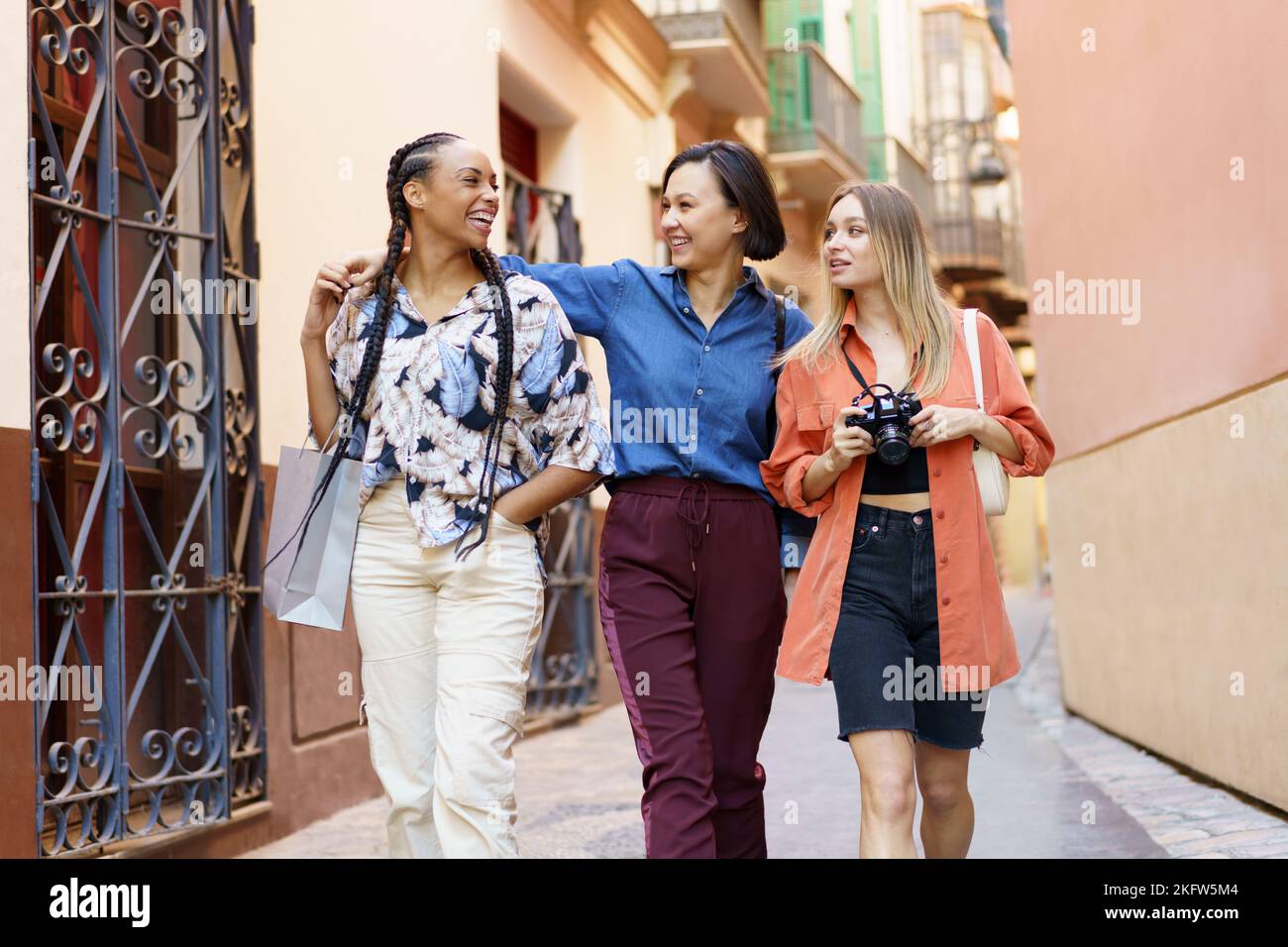 Happy multiracial ladies with camera against building Stock Photo