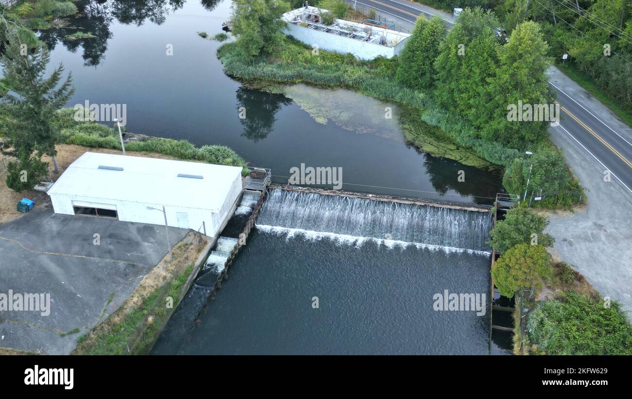 An aerial view of small dam on a river by asphalt road and lush green ...