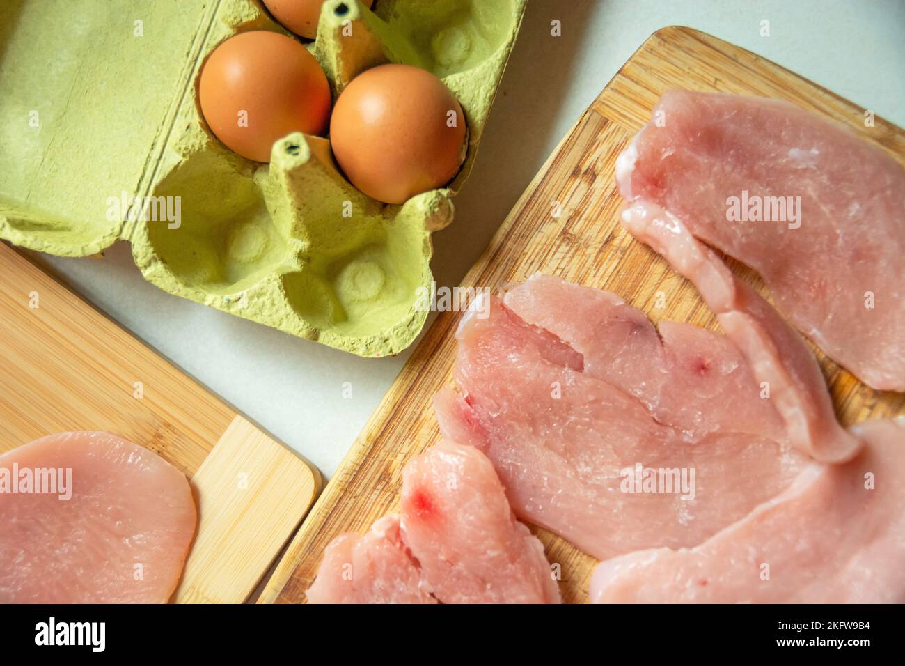 Eggs in a carton box and meat for chops on the table, top view Stock Photo