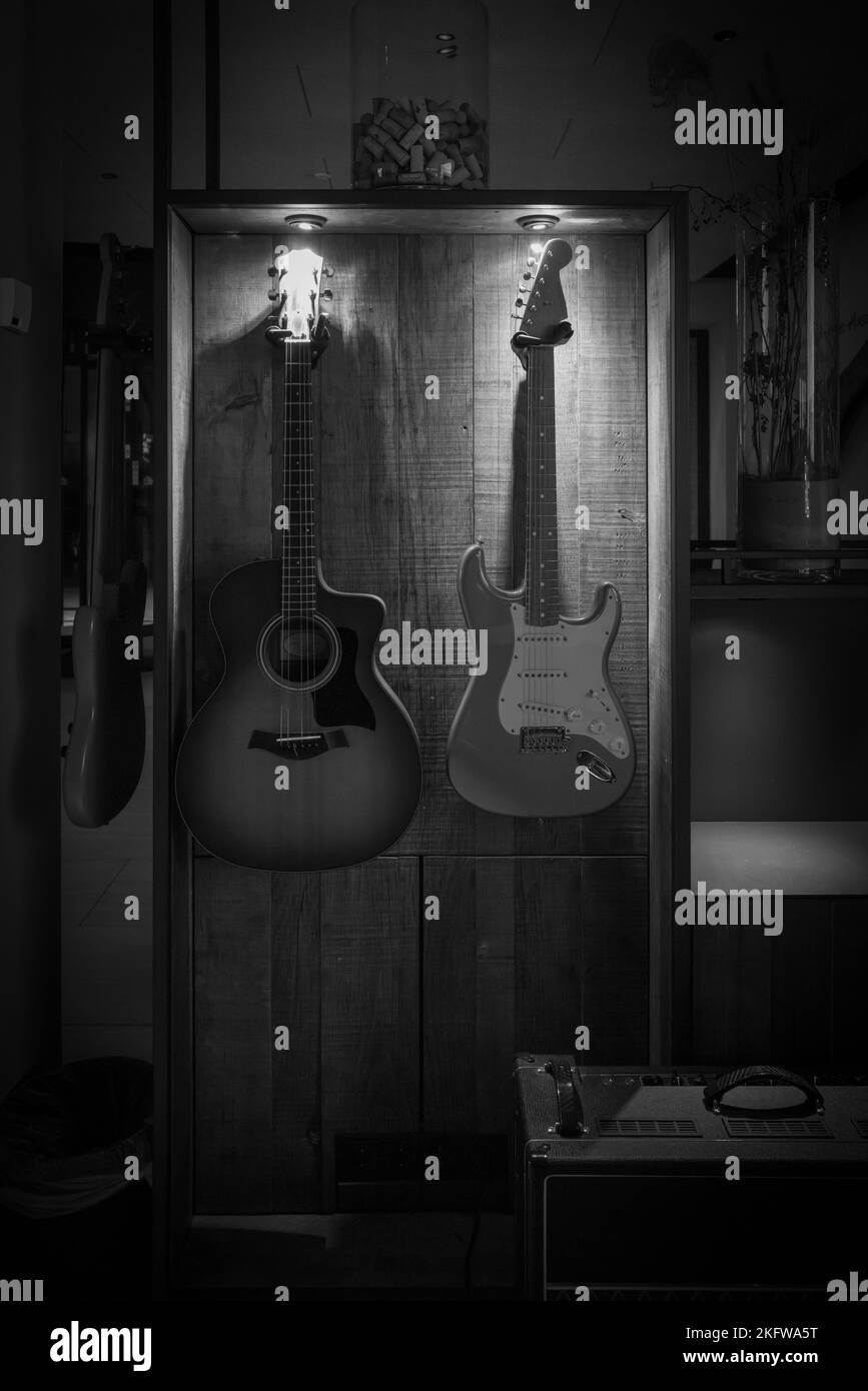on the wall hang an electric guitar and an acoustic guitar Stock Photo