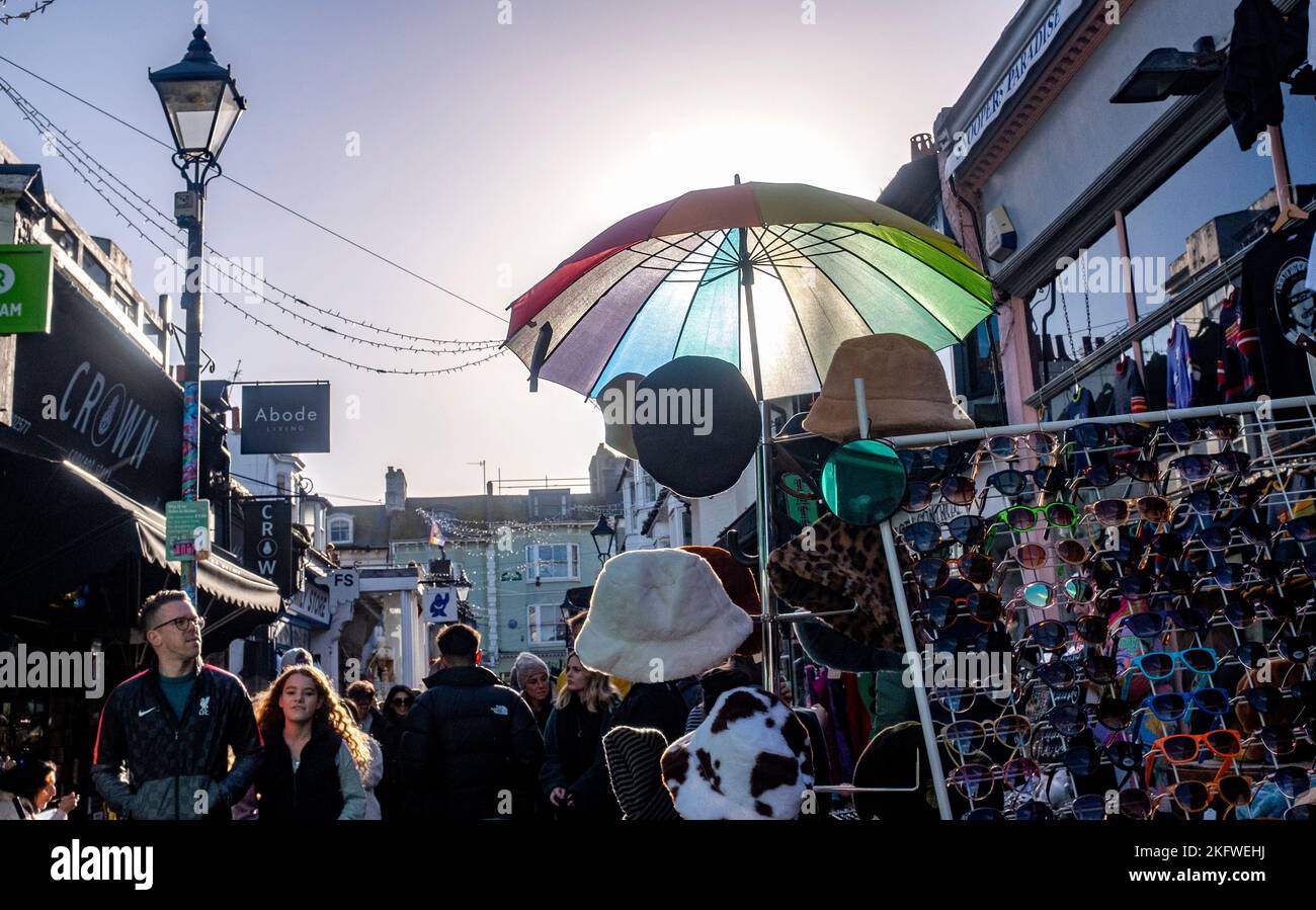 Brighton UK 20th November 2022 - A brightly coloured umbrella at a stall as The North Laine area of Brighton is busy with Christmas shoppers on a beautiful sunny day : Credit Simon Dack / Alamy Live News Stock Photo