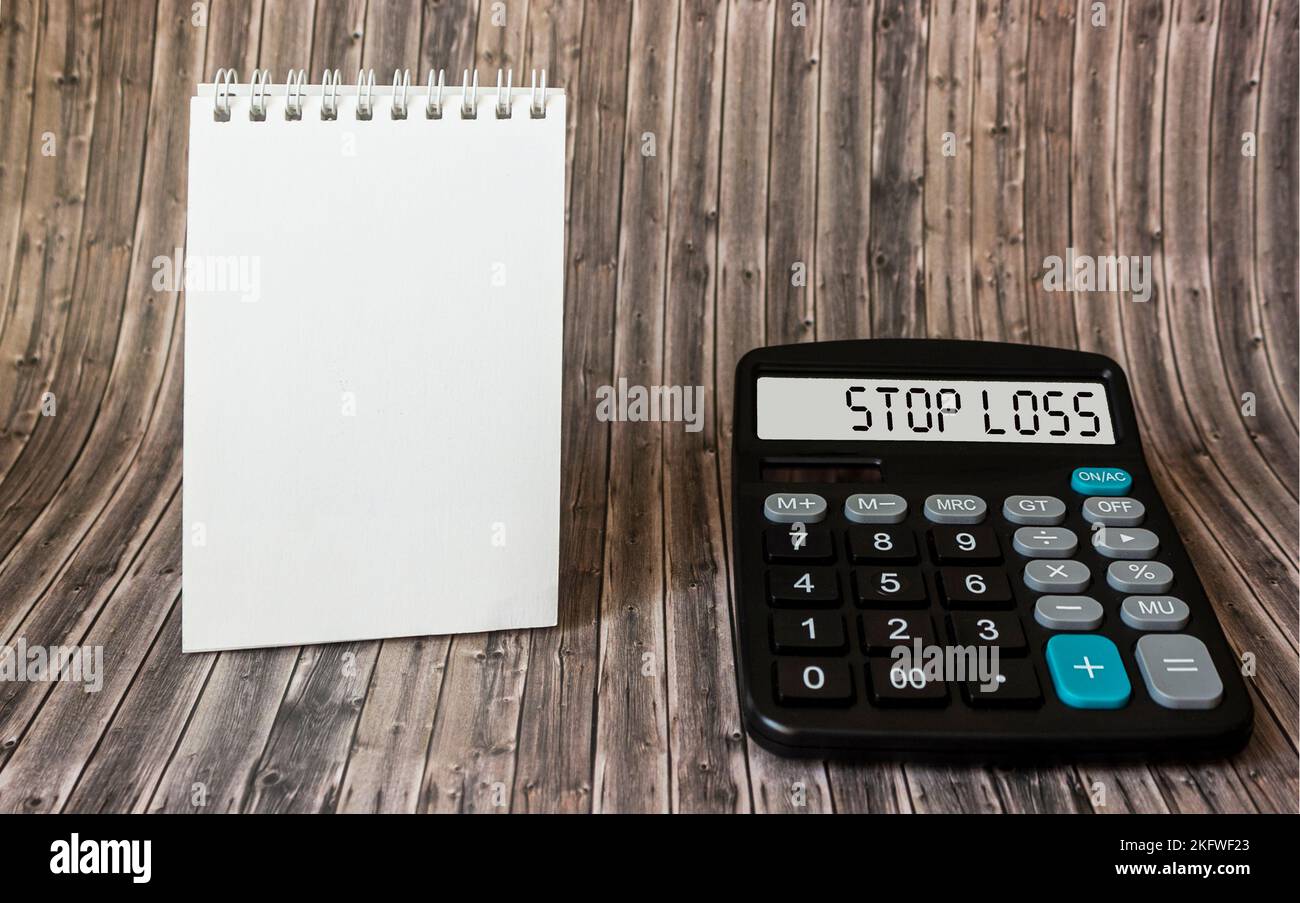Stop Loss concept on calculator display, on wooden table with notepad