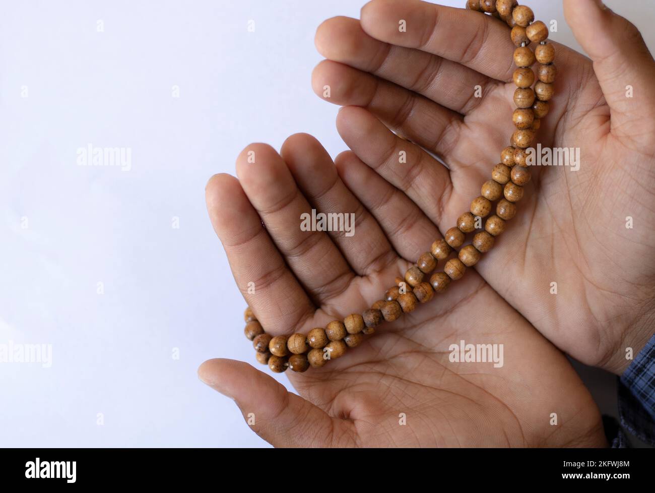 Asian young boy prays with open hands on a white background. Boy praying to god with the praying beads. Stock Photo