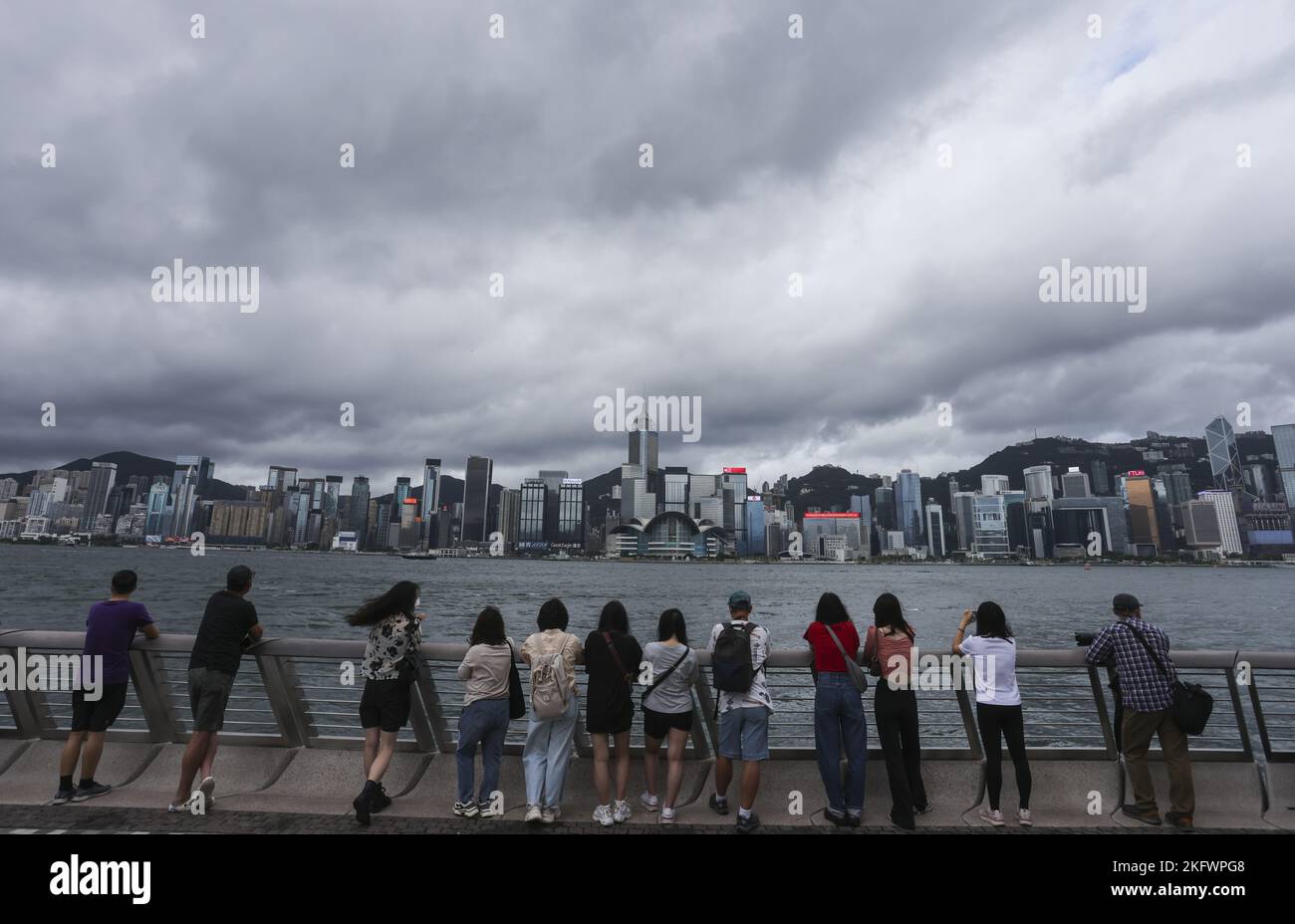 Members of the public watch the Government Flying Services helicopters carrying the national and SAR flags fly past and sea parade during the flag-raising ceremony at Golden Bauhinia Square in Wan Chai to celebrate the 25th anniversary of the establishment of the HKSAR, viewing from the Tsim Sha Tsui promenade, while police patrol and stand guard. 01JUL22 SCMP / Nora Tam Stock Photo