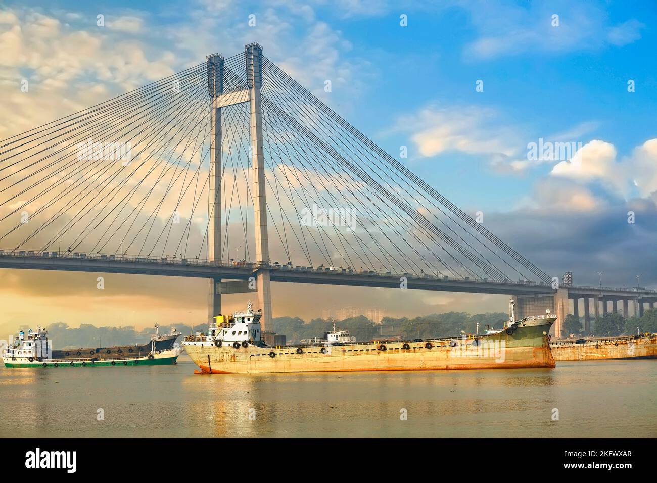 Freight ships on river Ganges near Vidyasagar Setu cable stayed bridge at sunrise at Kolkata, India Stock Photo
