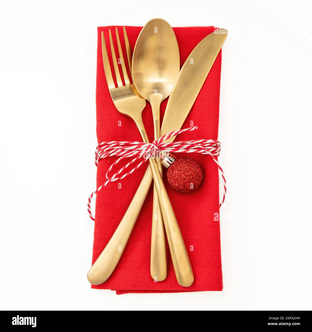 Christmas table setting, celebration dinner. Golden Cutlery and red cloth napkin isolated on white, top view Stock Photo