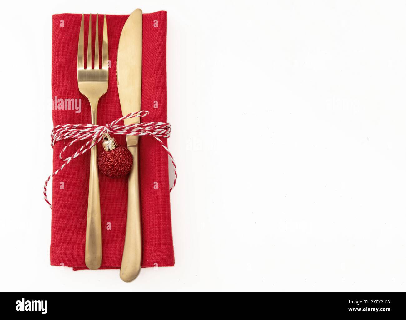 Christmas table setting, celebration dinner. Golden Cutlery and red cloth napkin isolated on white, top view, copy space Stock Photo