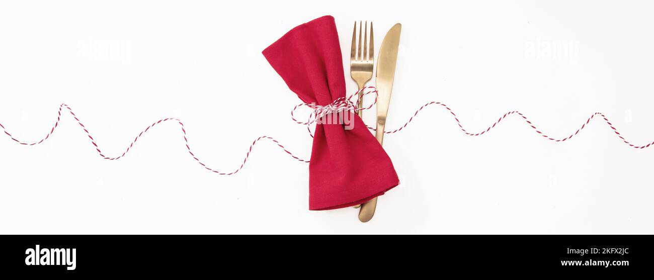 Holiday table setting. Golden Cutlery and red cloth napkin isolated on white, banner. Christmas New Year , celebration dinner Stock Photo