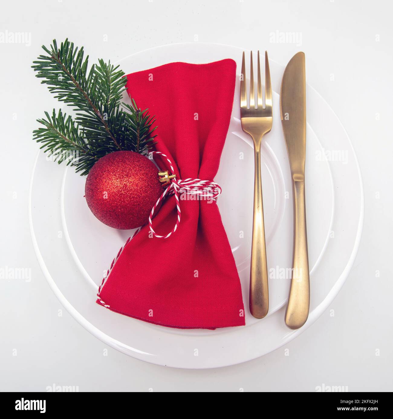 Christmas table setting, celebration dinner. Golden Cutlery and red cloth napkin on plates isolated on white, top view Stock Photo
