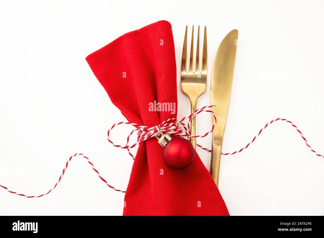 Christmas table setting, celebration dinner. Golden Cutlery and red cloth napkin isolated on white, top view, copy space Stock Photo