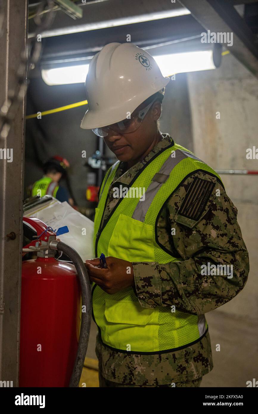 U.S. Navy Lt. Cmdr. Malia Gonzalez, Joint Task Force-Red Hill (JTF-RH) Safety Advisor, inspects a fire extinguisher during a Red Hill Bulk Fuel Storage Facility (RHBFSF) Stakeholder Safety Walkthrough at the facility in Halawa, Hawaii, Oct. 12, 2022. JTF-RH was established by the Department of Defense to ensure the safe and expeditious defueling of the RHBFSF. Stock Photo