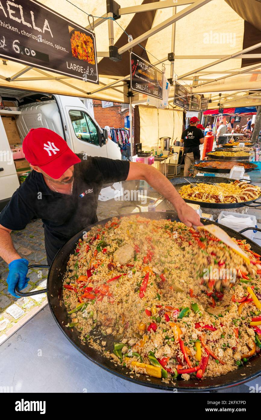 https://c8.alamy.com/comp/2KFX7PD/outdoor-food-stall-with-a-row-of-large-skillet-pans-cooking-various-foods-with-a-man-in-foreground-stirring-the-first-one-full-of-steaming-paella-2KFX7PD.jpg