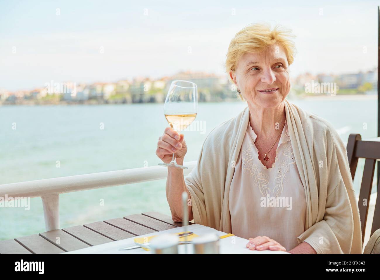 Elderly woman traveler sitting alone on the terrace of coffee shop