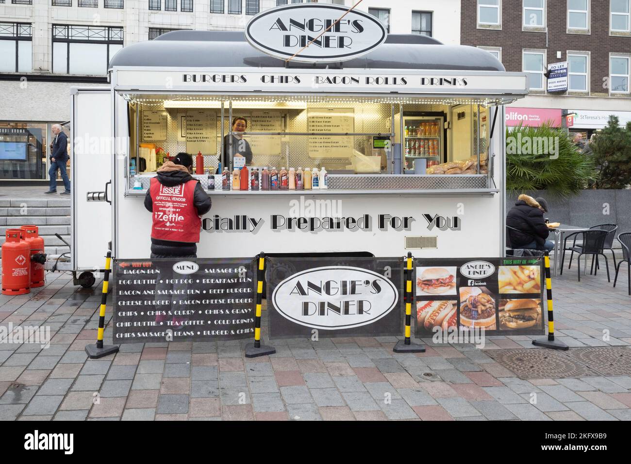 A Big Issue Vendor,  buying food and drink at Angie's Diner fast food stall in the weekly Market Darlington Co. Durham England UK Stock Photo
