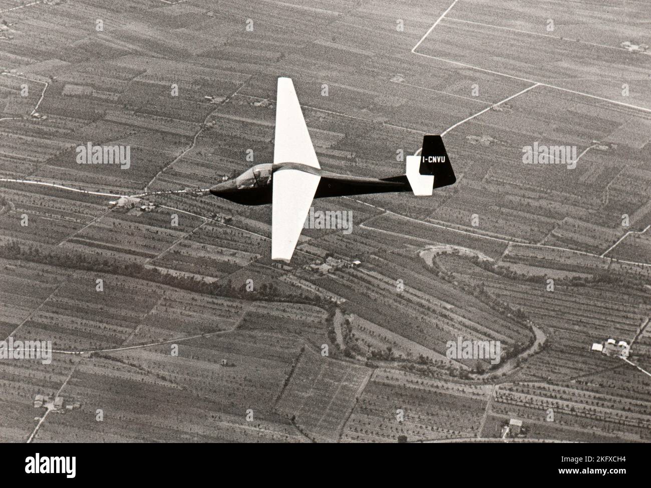 A glider soars over the countryside of Piedmont (Italy) in mid fifties Stock Photo