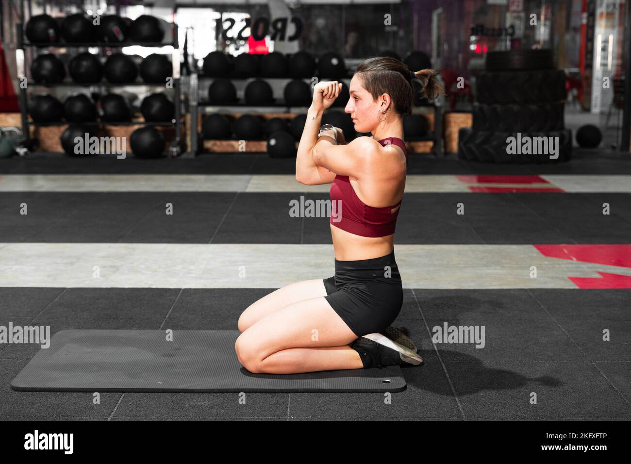 concentrated caucasian young woman exercising on the gym floor on a ...