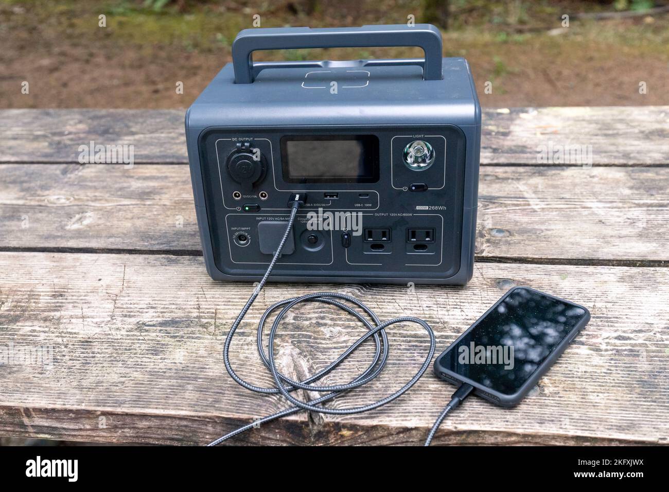 Portable Power Generator charging a smartphone - small emergency generator or good for car camping vanlife Stock Photo