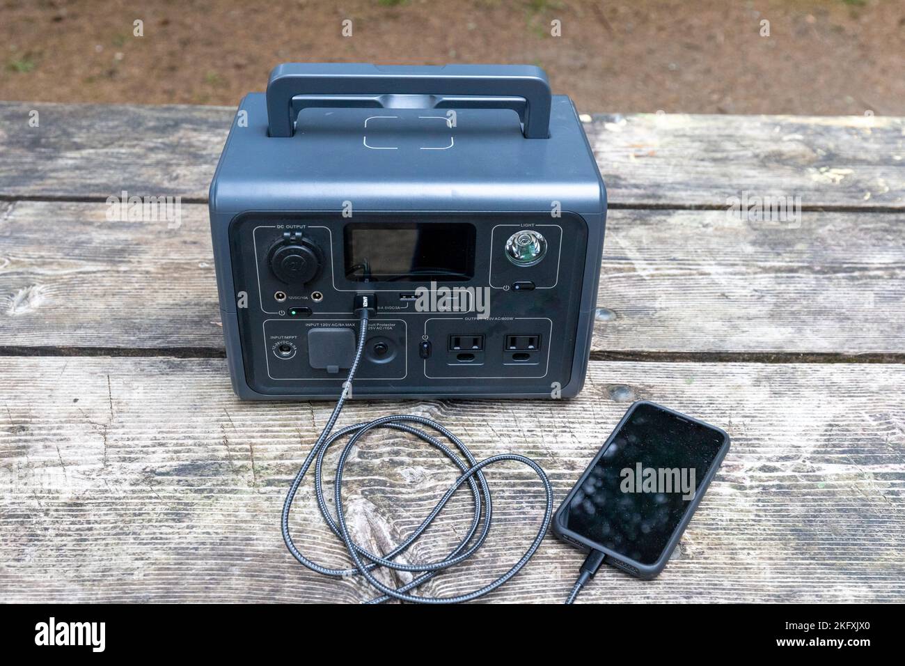 Portable Power Generator charging a smartphone - small emergency generator or good for car camping vanlife Stock Photo