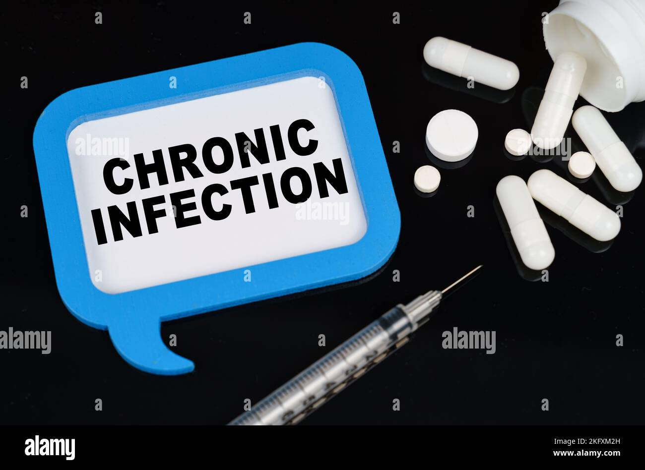 Medical concept. On a black surface, a syringe, pills and a blue frame ...