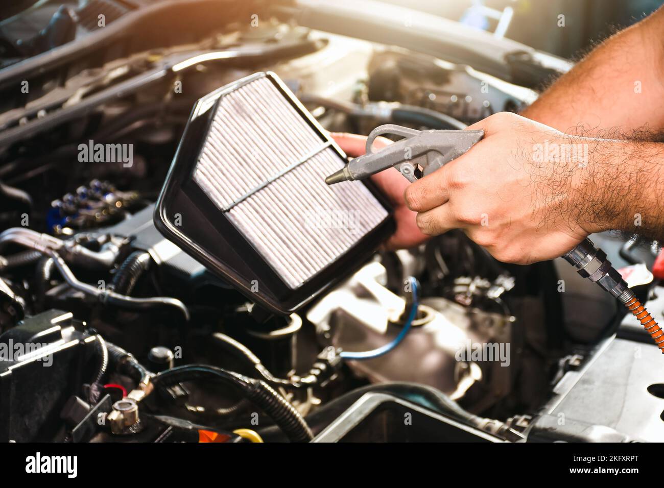 Auto mechanic hand is blowing dust and cleaning a car air filter with