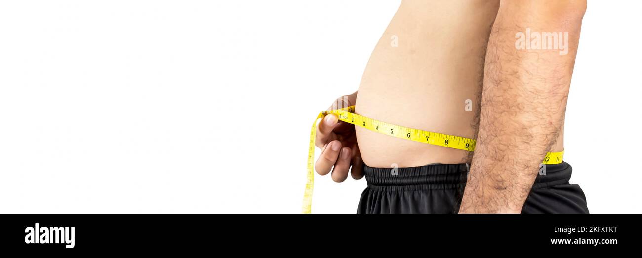 A chubby Asian man measures his waist with a yellow tape measure,panoramic horizontal copy space on white background,Healthcare concept Stock Photo