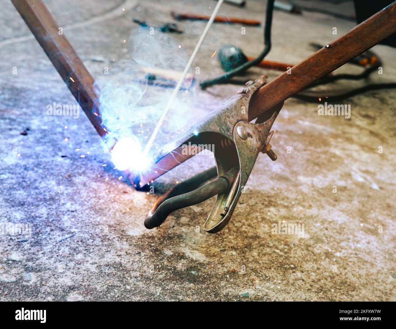 The welder negative clamp is clamped on the steel rod for welding Stock