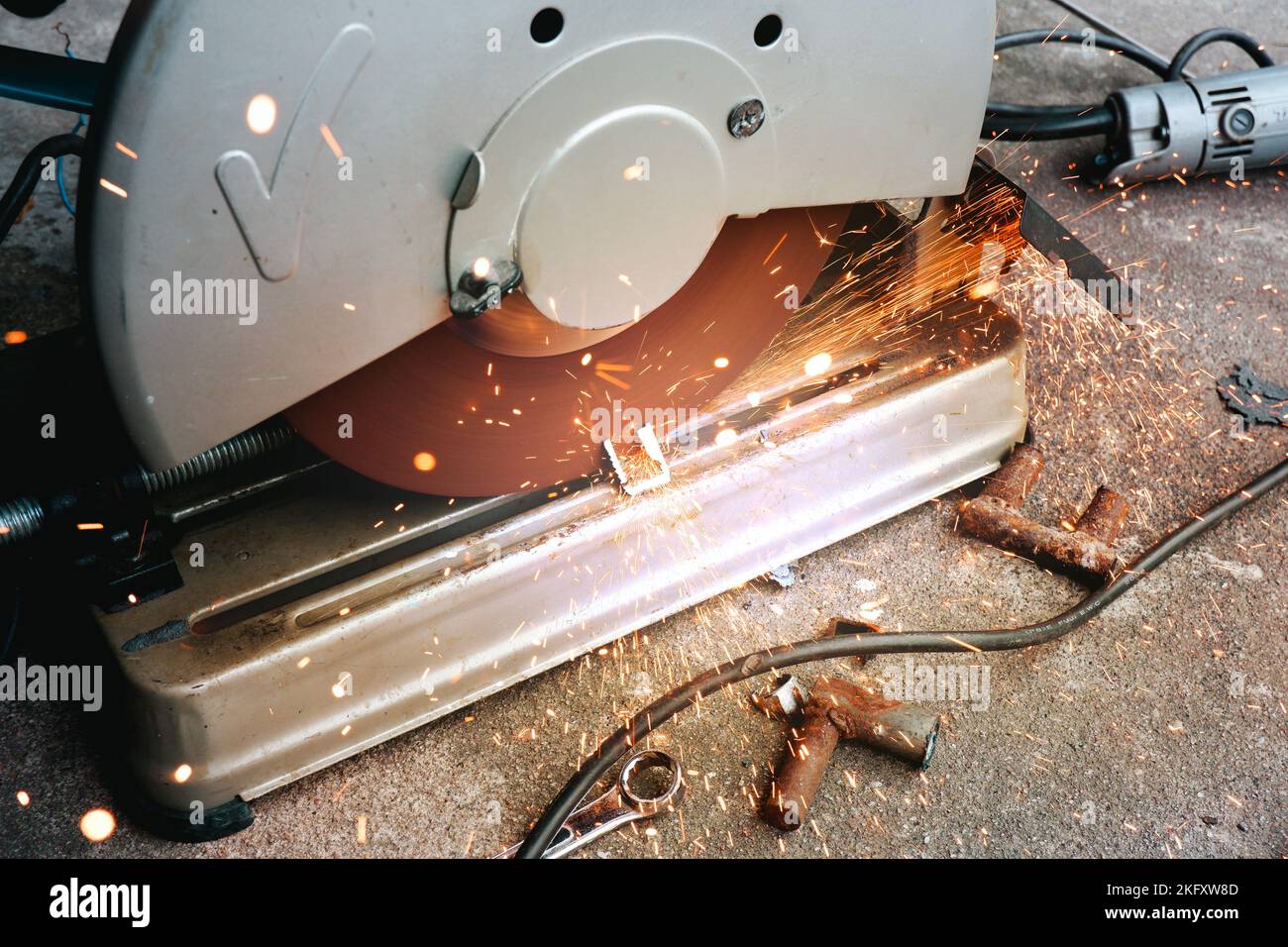 A mechanic is using a cut off saw to cut steel pipes in a factory Stock