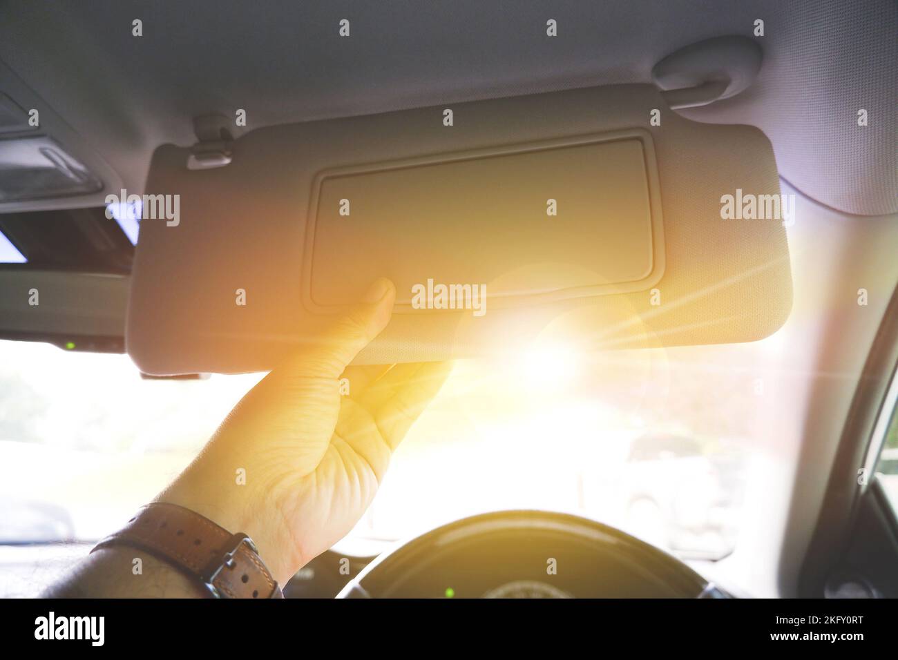 Driver manually adjusting the sun visor in order to block sunlight in a