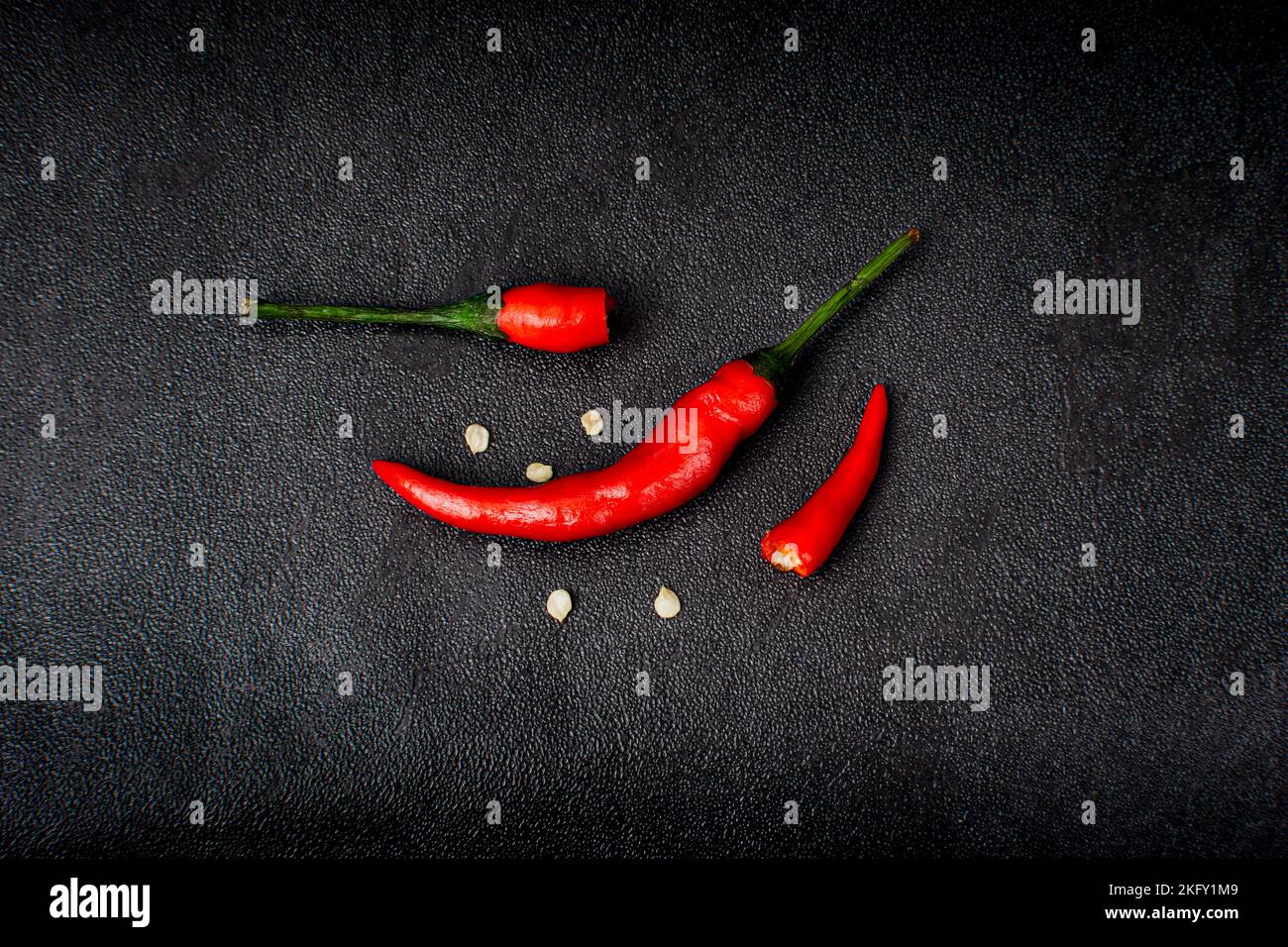 Red hot chilli peppers and half broken chilli on a black background Stock Photo