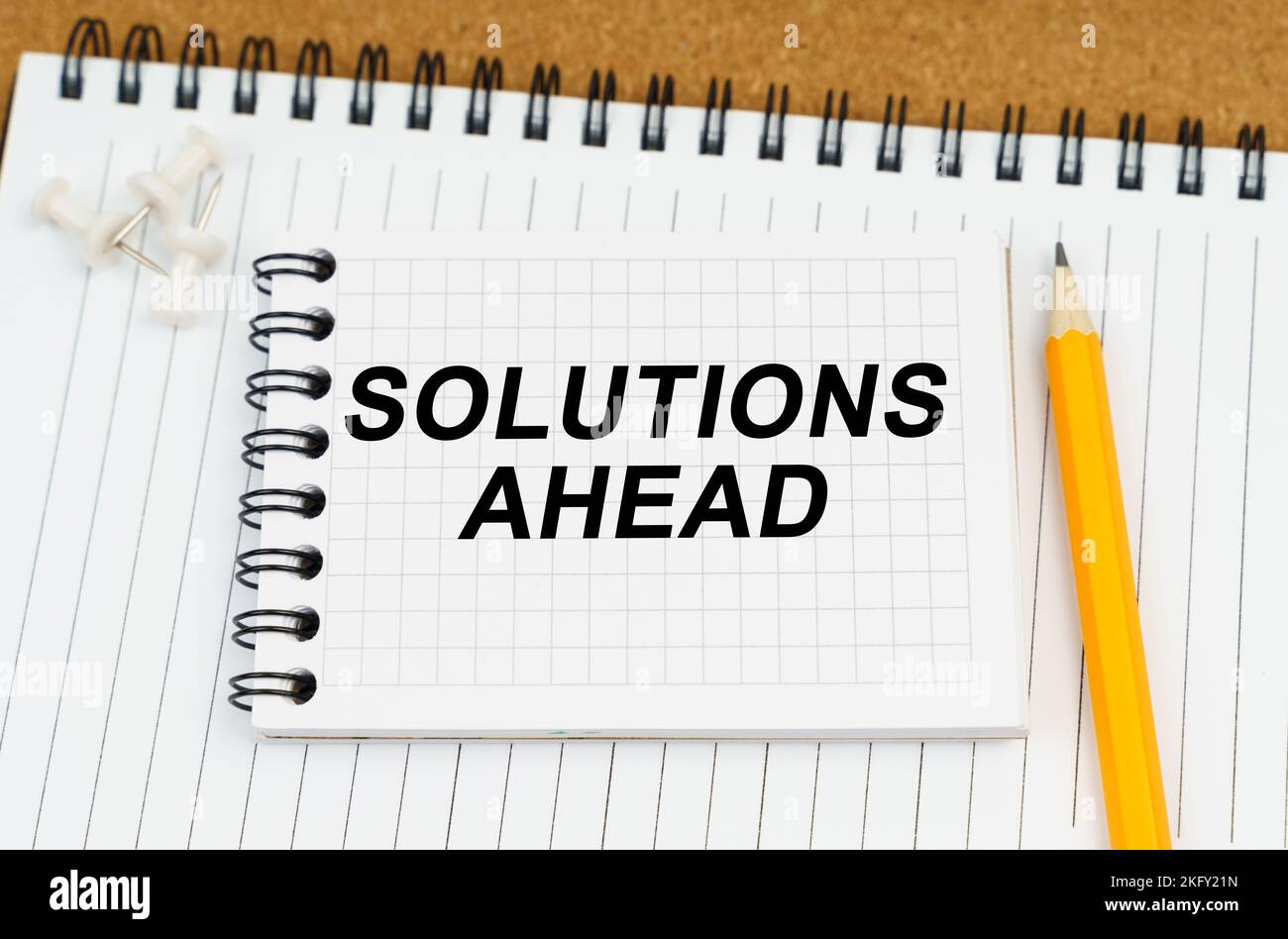 Business and economy concept. There are two notebooks and a pencil on the table. On the top notepad, the inscription - Solutions Ahead Stock Photo