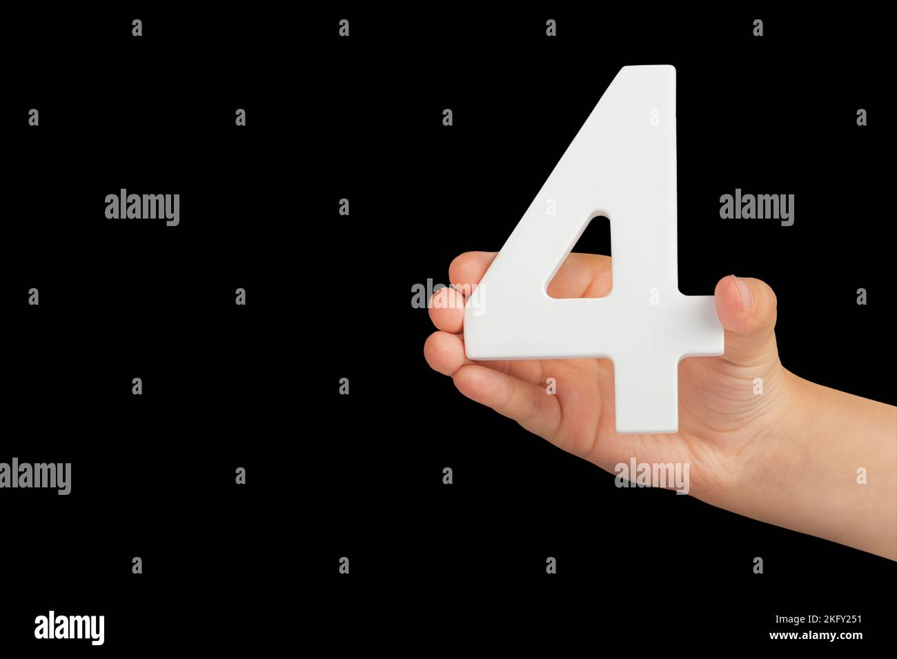 Number four in hand isolated on black background. Number four in a child's hand, holding on a black background. To be inserted into a project or Stock Photo