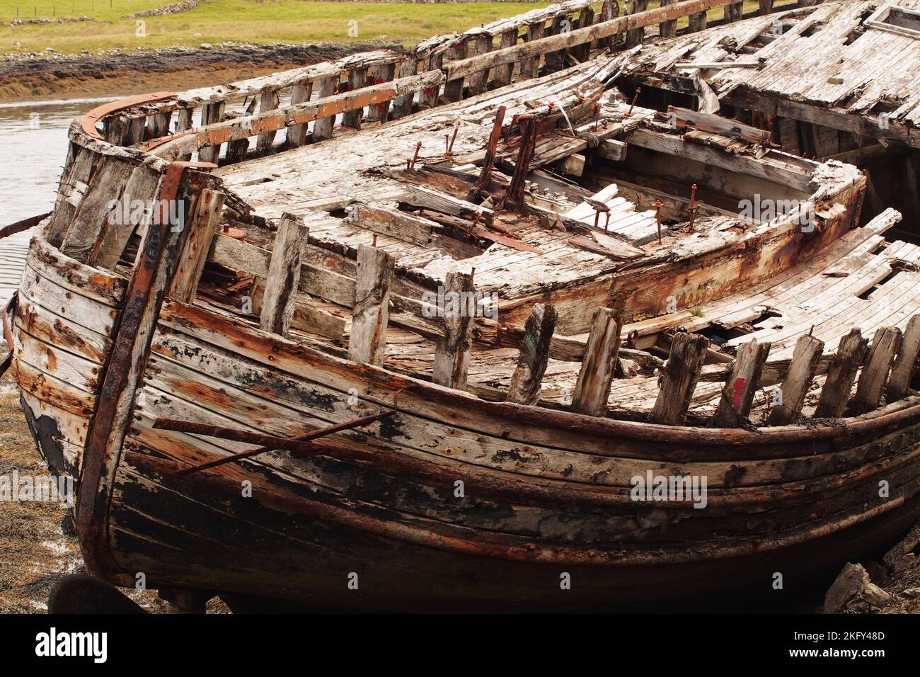 An large, old, wrecked wooden boat, in dry dock, showing the rotting
