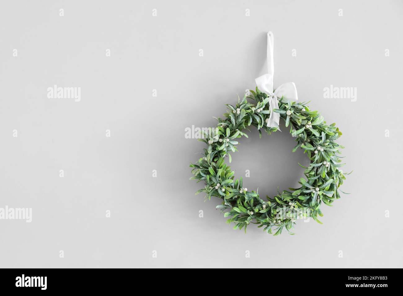 Christmas mistletoe wreath hanging on grey wall in room Stock Photo Alamy