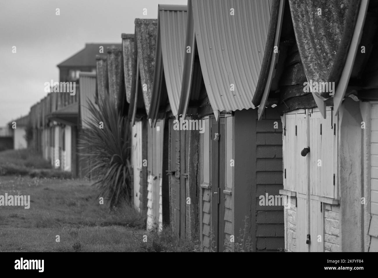 Traditional British wooden beach huts with curved tin roofs, lined up along the sea front. Stock Photo