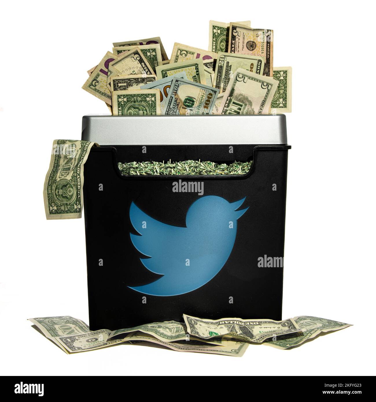 A pile of American dollars being shredded by a machine with a twitter logo Stock Photo