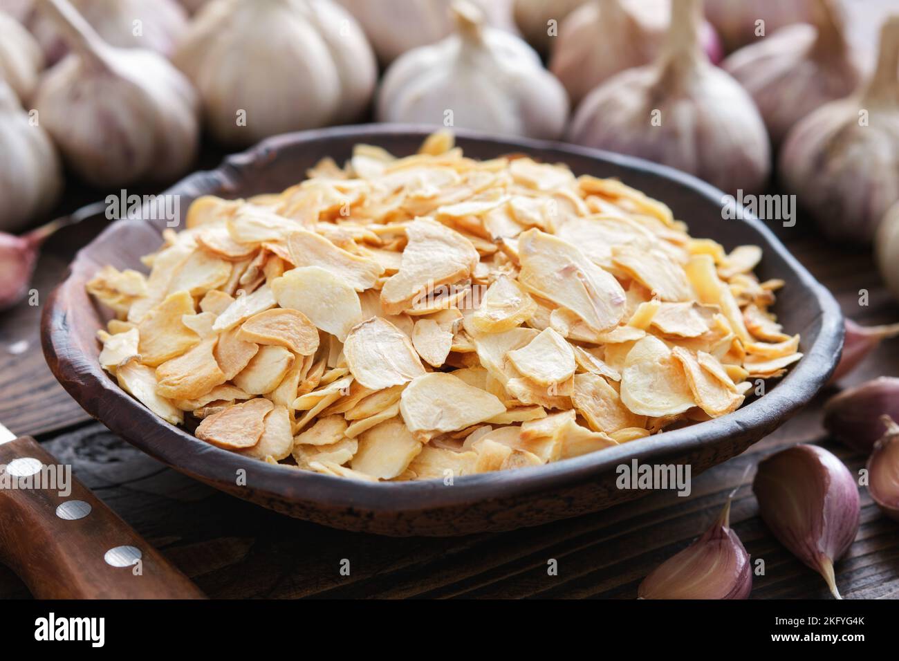 Bowl of dried garlic flakes, garlic cloves. Heads of garlic on