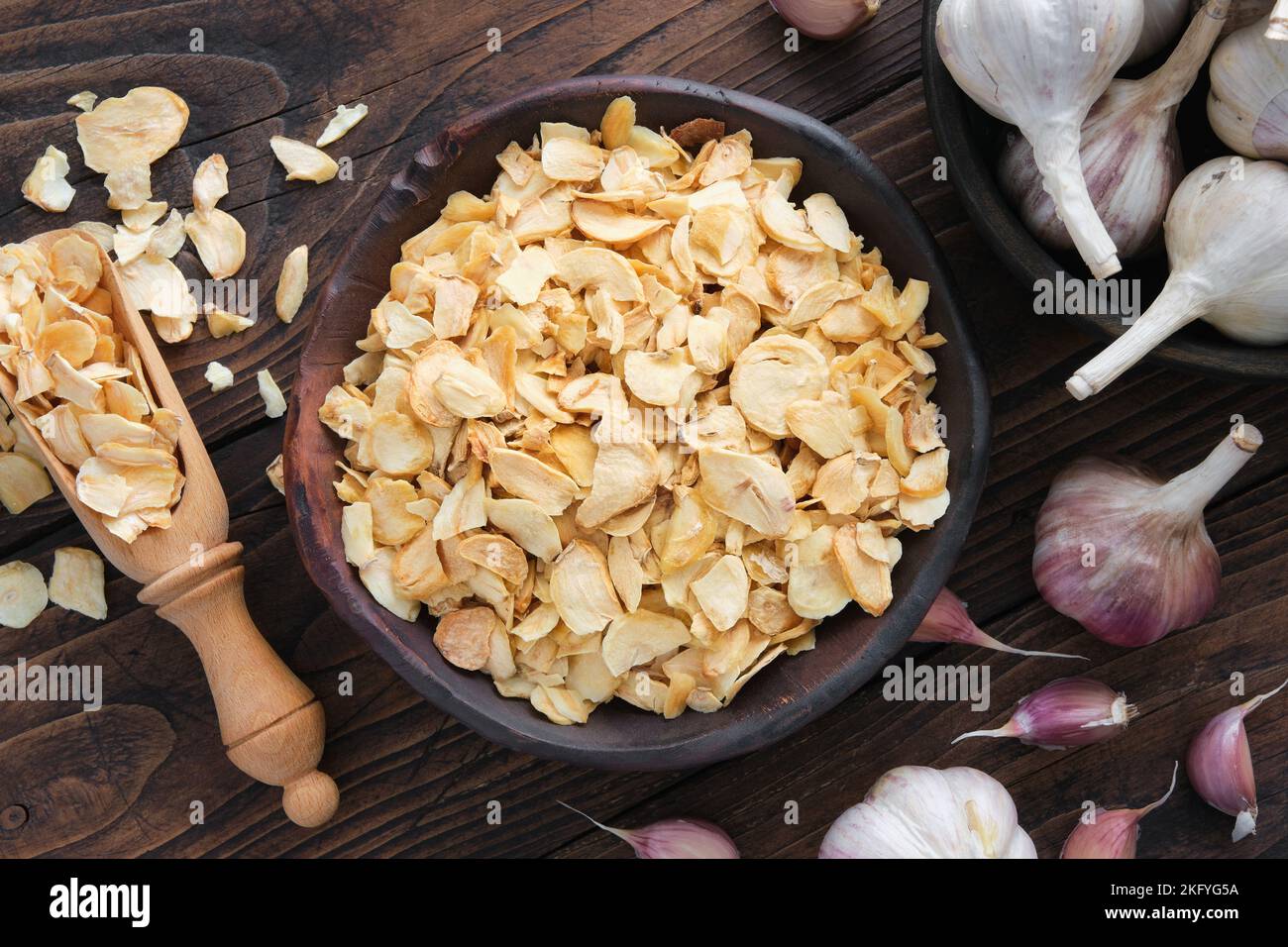 Bowl of dried garlic flakes, garlic cloves. Heads of garlic on kitchen