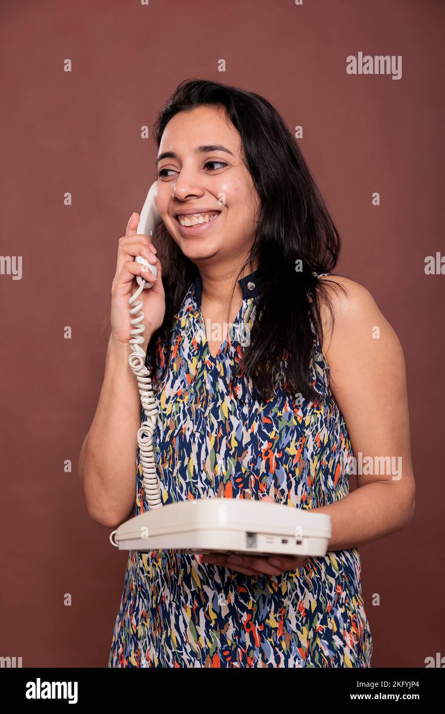 Smiling indian woman answering landline phone call, customer support