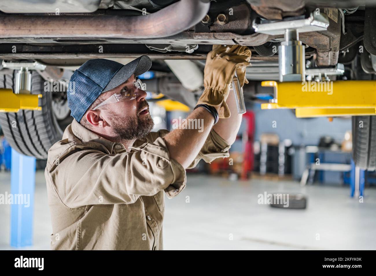 Professional Middle Aged Mechanic Fixing Undercarriage of the Vehicle