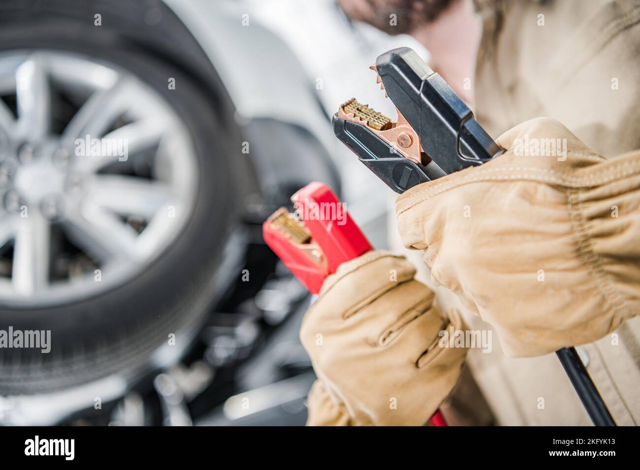 Closeup of Car Mechanic’s Hands Holding Booster Cables for Vehicle