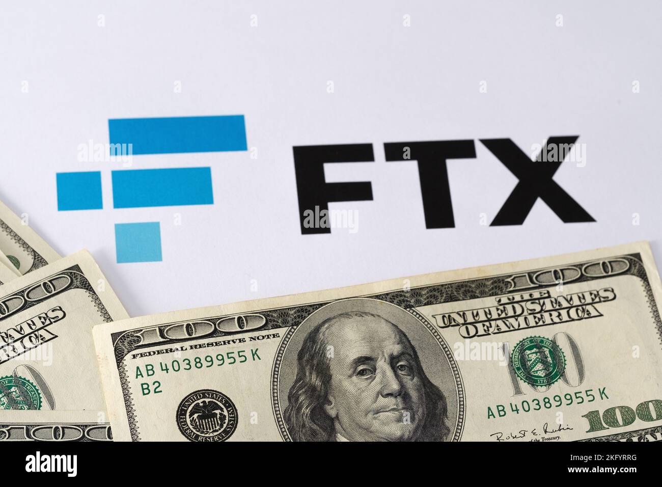 FTX Cryptocurrency Exchange logo printed on paper and US dollars banknotes around it. Concept for company bankruptcy and debt. Stafford, United Kindom Stock Photo