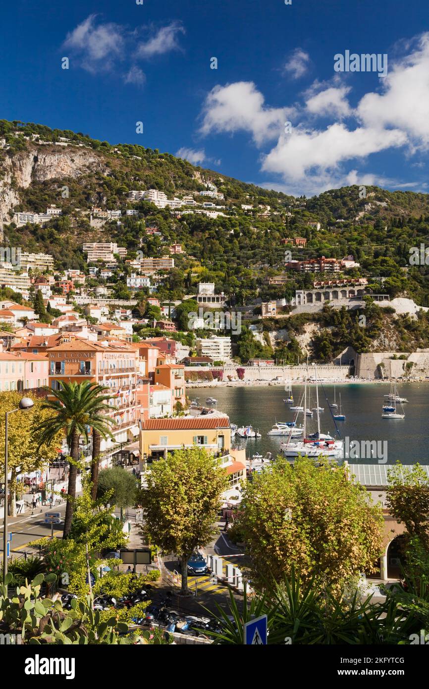 Colourful apartment and Welcome hotel building facades and harbour with pleasure boats and sailboats anchored in bay, Villefranche-sur-Mer, Provence. Stock Photo