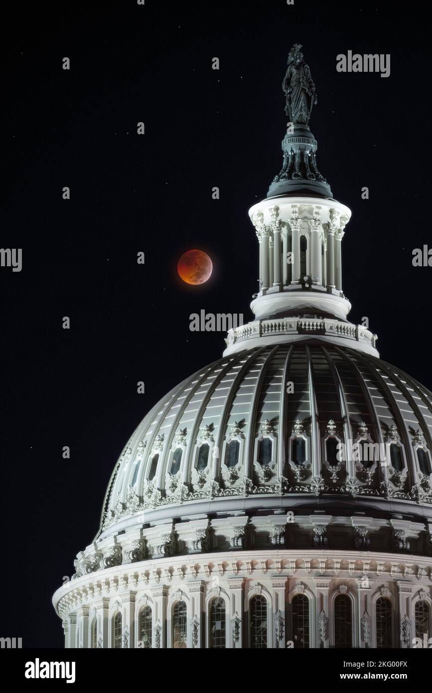 A total lunar eclipse from November 8th, 2022 glows its amber red color over the US Capitol dome. Stock Photo
