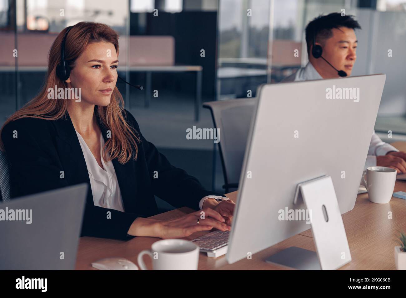 Businesswoman in headphones working on computer while sitting in modern ...