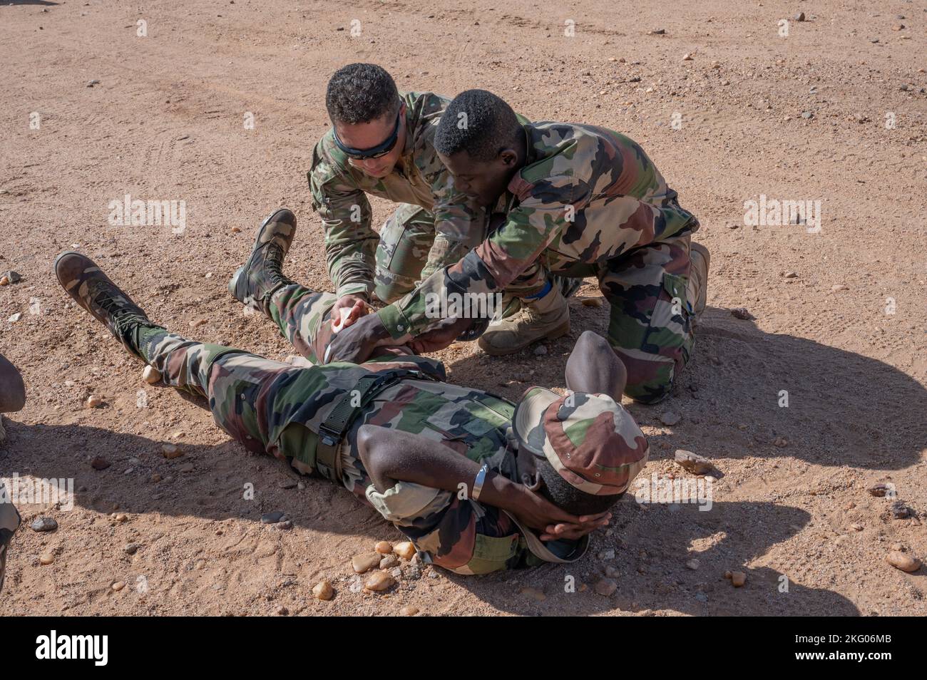 AIR BASE 201, Niger - U.S. Army Sgt. 1st Class Eric Saint-Lo (left), 443rd Civil Affairs Battalion medic, demonstrates how to properly place a tourniquet on a simulated wounded individual at Air Base 201, Niger, Oct. 17, 2022. The partnership between the U.S. and Africa is critical to overcoming geographic challenges and building an international model of security cooperation across the continent. Stock Photo