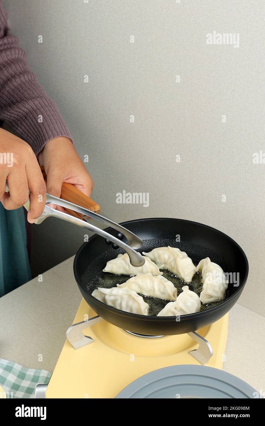 Female Asian Hand Cooking Gyoza Japanese Dumpling in Hot Oil using