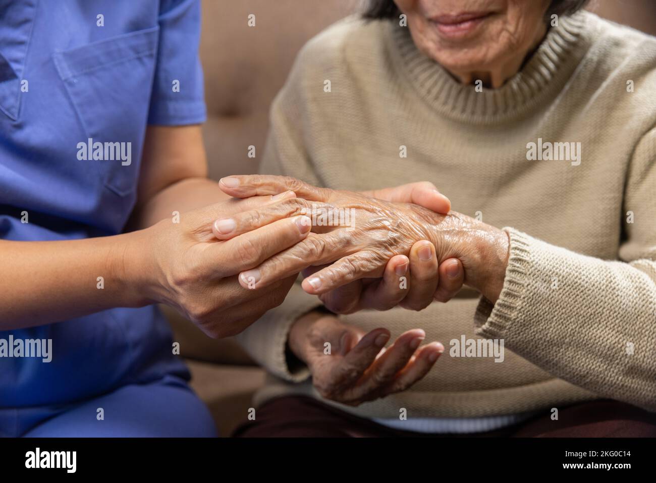 Caregiver massaging wrist of elderly woman in painful swollen gout . Stock Photo