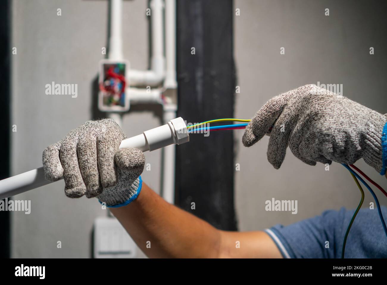 Electrician pulling wire into PVC Conduit Stock Photo